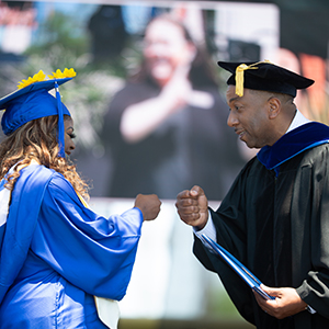 Chancellor fist bumping female student