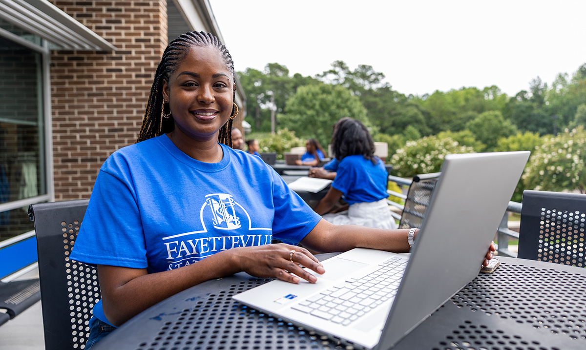 Person Wearing a Fayetteville State University Shirt and Using A Laptop