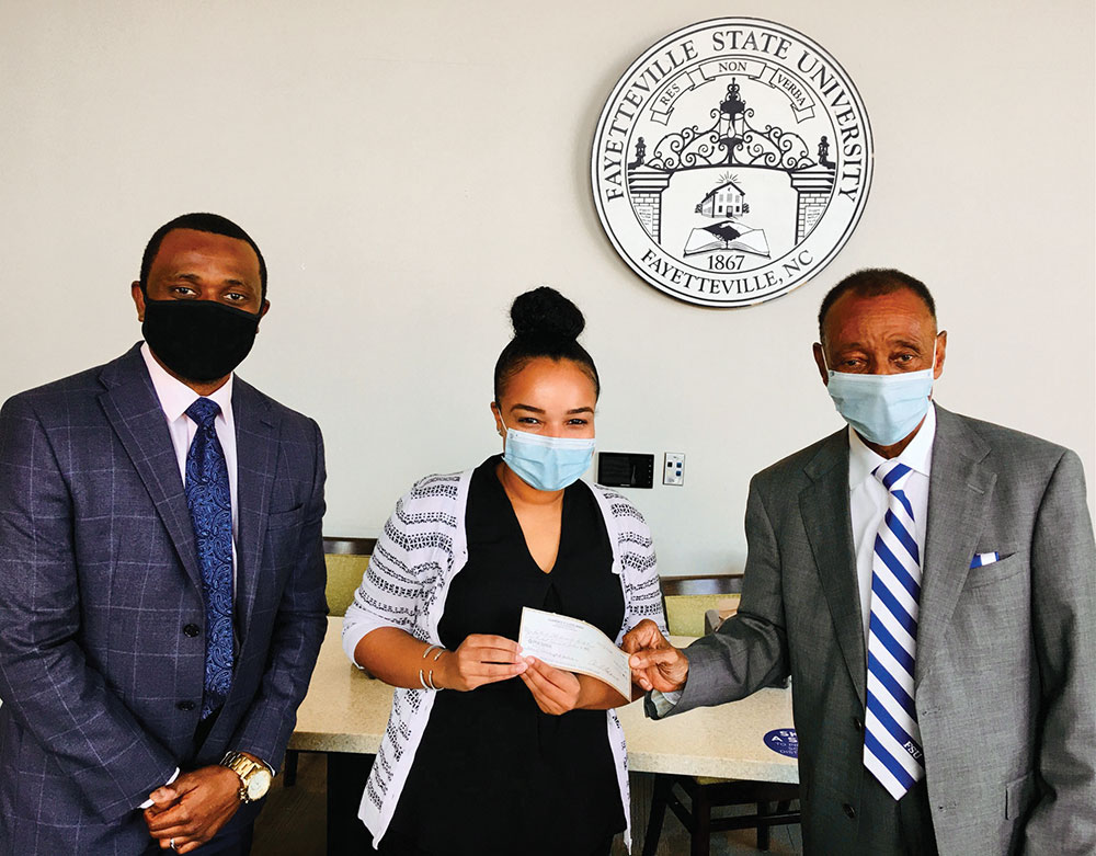 Chris Davis, Associate Vice Chancellor for Development, and Jasmin Sessoms, Interim Director of Alumni Affairs, accept a donation from Dr. Clarence E. Lloyd